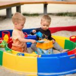 Kinder spielen mit Wasser und Sand