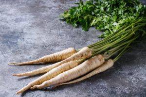 Ein Bund frischer Pastinaken mit Grün.