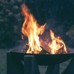 Schwarze Feuerschale mit lodernden Flammen im Freien