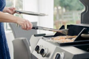 Eine Frau grillt an einem Gasgrill