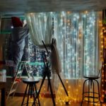Lichternetz/ Lichtervorhang leuchtet vor einer großen Fensterfront.