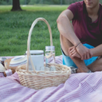 Mann sitzt auf Decke mit Picknickkorb