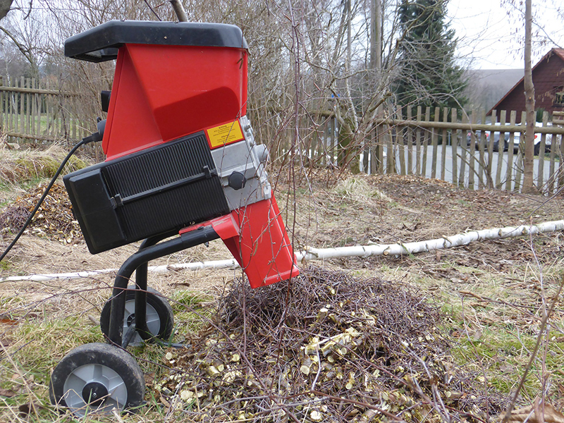 Ein roter Gartenhäcksler steht im Garten